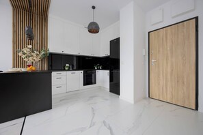 Une cuisine moderne avec des armoires blanches, un comptoir noir et un sol en marbre.