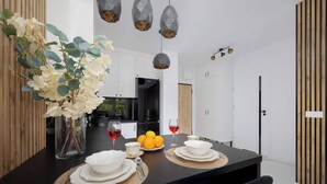 Eine moderne Küche mit einer zentralen Kochinsel, einem Essbereich mit einem schwarzen Tisch und einer Vase mit weißen Blumen.