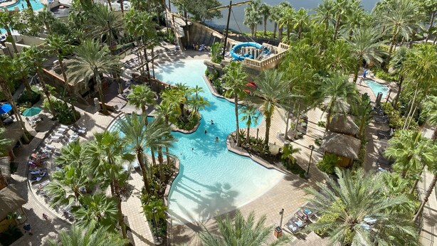 Ein Resort mit mehreren Schwimmbecken, umgeben von Palmen und Liegebereichen.
