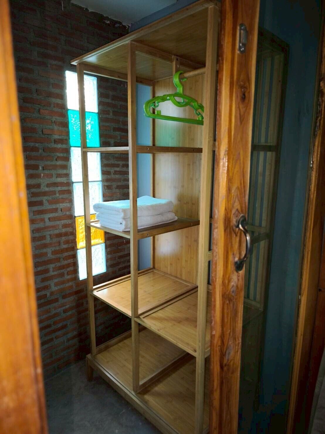 Een houten garderobe met verschillende planken, een kledingstang en een deur met een handgreep.