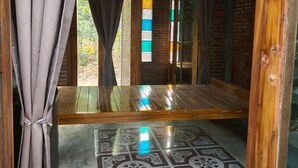 A room with a wooden floor, a patterned tile floor, a window with a view of greenery, and a ceiling with exposed beams and lighting fixtures. - Phawaeng Resort (Uthai Thani)