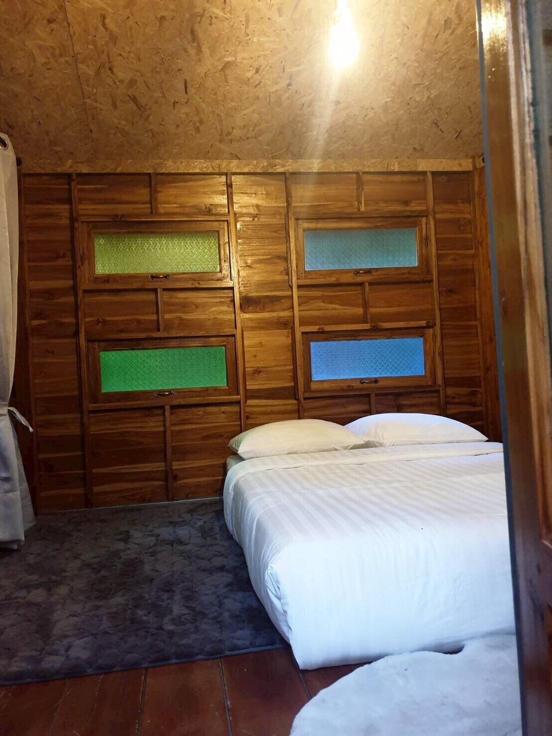 Una habitación con paneles de madera, una cama, una alfombra pequeña y un ventanal con vistas.