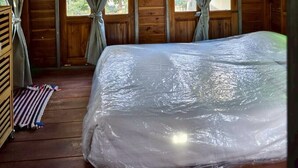 A wooden cabin room with a bed, curtains, and a window. - Phawaeng Resort (Uthai Thani)