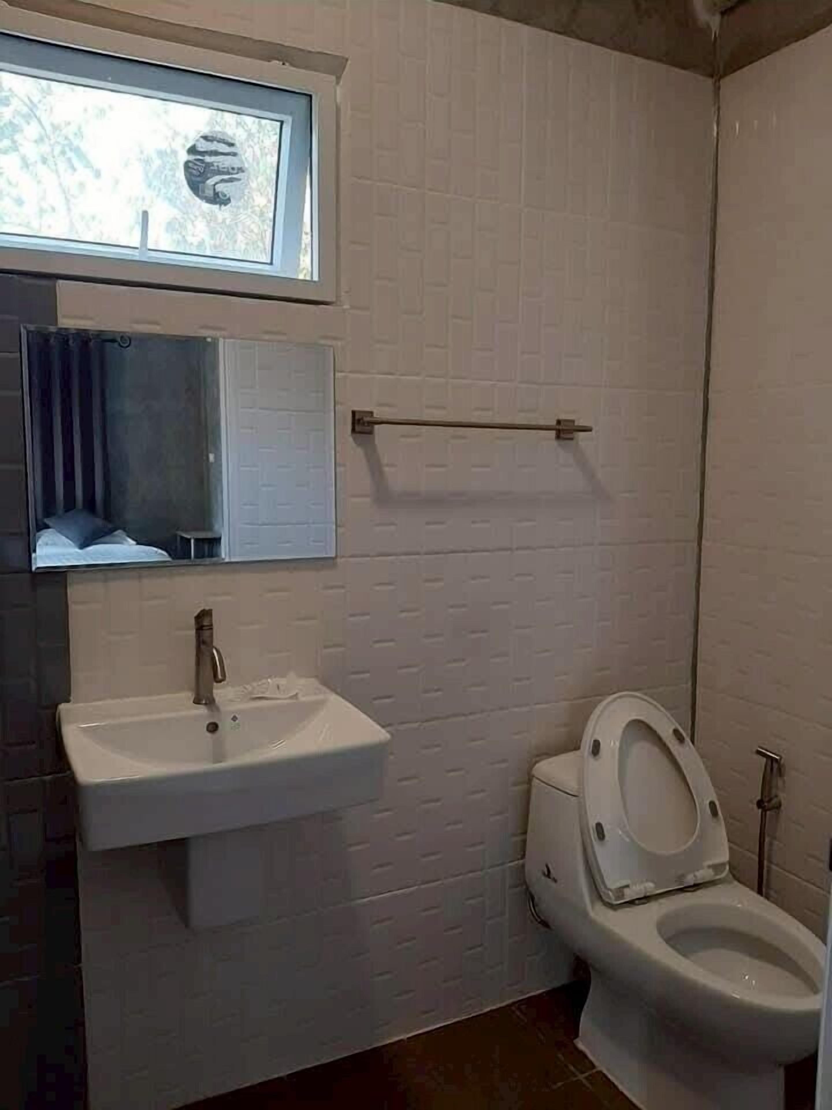 A bathroom with a white sink, a toilet, and a window above the sink.