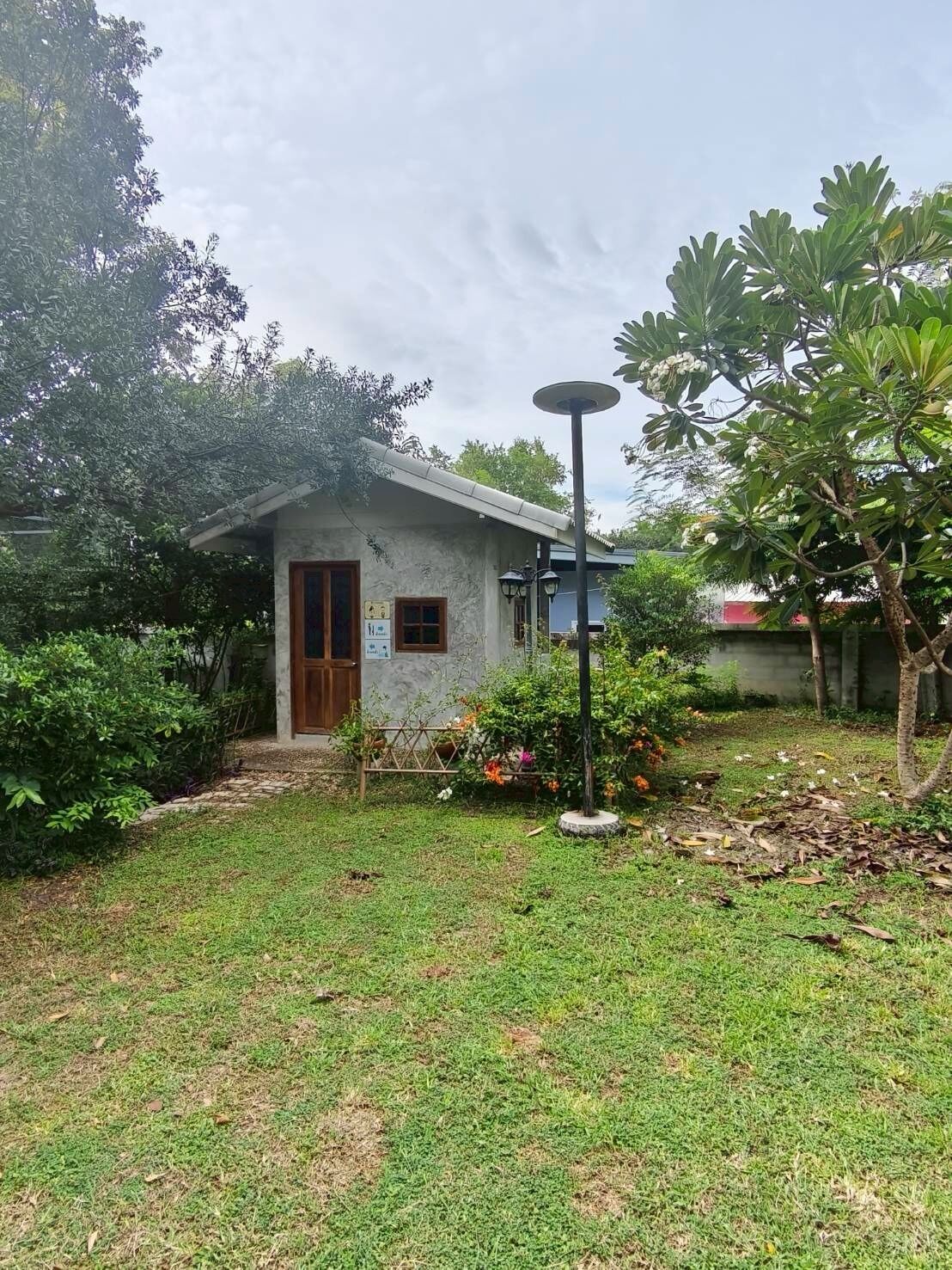 A small building with a door and windows, surrounded by a grassy area and some trees.