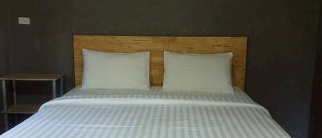 A bed with a wooden headboard, two pillows, and a wall-mounted tree decoration.