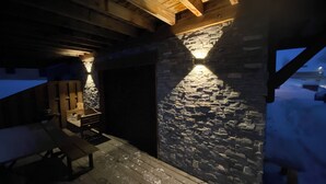A stone wall with a wooden staircase leading to a dark doorway.
