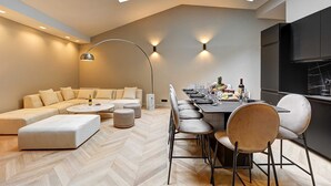 A modern loft with a dining area, a sofa set, and a herringbone floor. - Elegant Apartment With AC - 3br/10p- Le Marais (Paris)
