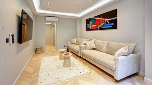 A modern living room with a sofa, a coffee table, and a flat-screen TV mounted on the wall. - Elegant Apartment With AC - 3br/10p- Le Marais (Paris)