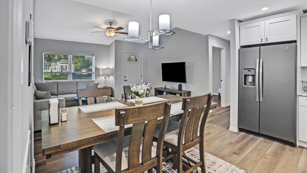 A modern kitchen with a built-in refrigerator, a dining area with wooden chairs and a table, and a ceiling fan. - Sparkling 3-bedroom house with AC in Palatka (Palatka)