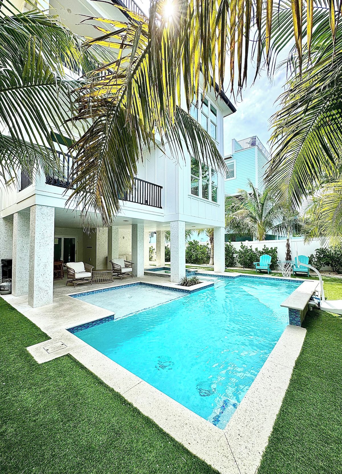 Une maison moderne dotée d’une piscine, de mobilier d’extérieur et de palmiers.