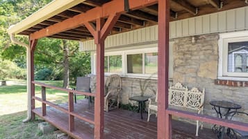 A covered outdoor area with a wooden deck, stone wall, and a window.