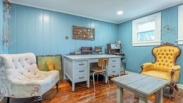 A room with a desk, two chairs, a table, and a window.