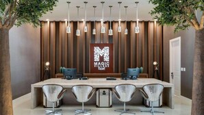 Een receptie met een houten paneelwand, een groot bureau met computers en vier stoelen.