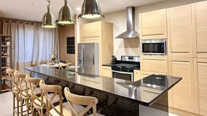 Een moderne keuken met een centraal kookeiland, roestvrijstalen apparatuur en houten kasten.