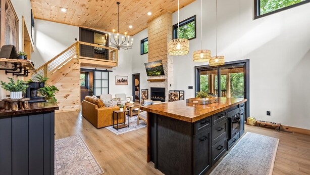 A spacious kitchen with a large island, wooden flooring, and a fireplace. There is a staircase leading to an upper level, and a cozy seating area with a fireplace.