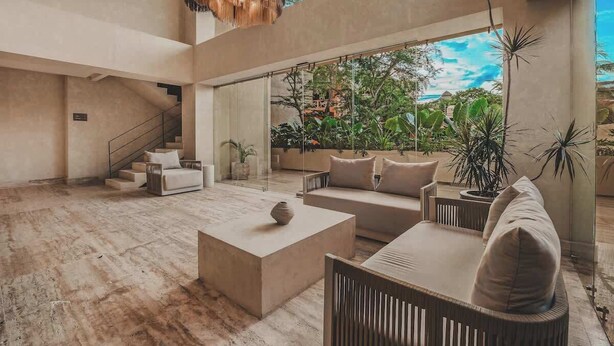 Amplia sala de estar con un gran ventanal, una escalera y una lámpara moderna.