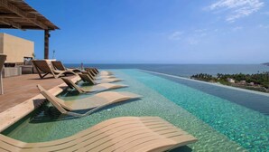 Una piscina con sillones de descanso y vista al océano.