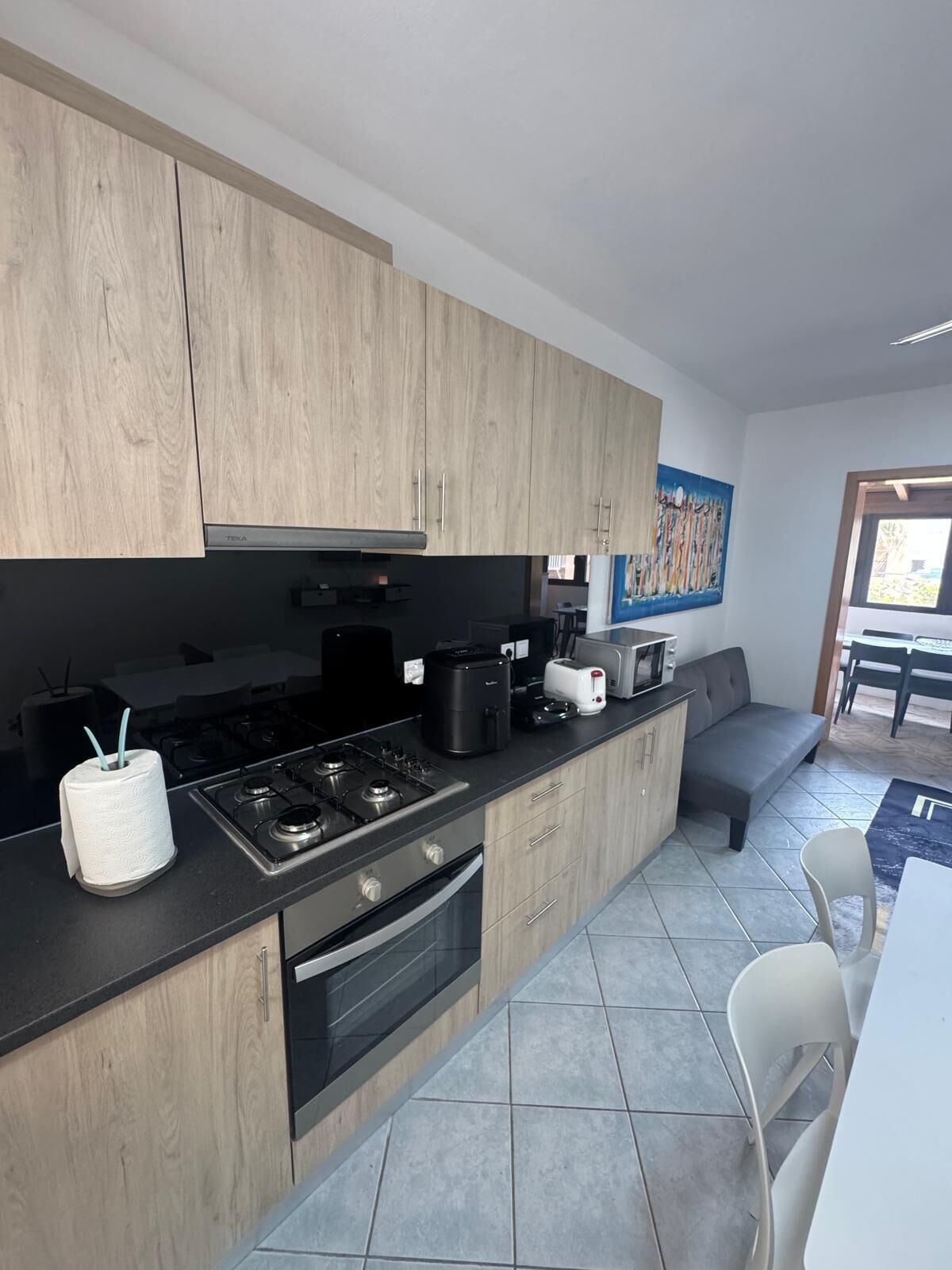Una cocina moderna con armarios de madera, estufa a gas, cafetera y tostadora.