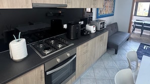 A modern kitchen with wooden cabinets, a gas stove, a coffee maker, and a toaster.