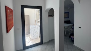 A hallway with a tiled floor, a door leading to a room with a bed, and a small table with chairs.