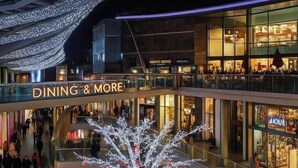 A multi-level shopping mall with a prominent 'DINING & MORE' sign, glass railings, and a large illuminated Christmas tree. - Central Apt Sleeps 8 | Bars, Restaurants & Parking (Merseyside)