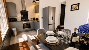 A modern kitchen with a dining area set for a meal, including a table with plates, glasses, and a bottle of wine. - City Centre Apt–Sleeps 6, Parking, Shops & Trains (Merseyside)
