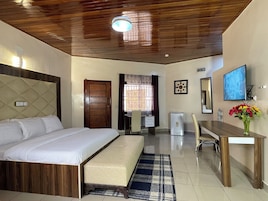 Habitación de hotel con cama, escritorio, silla, televisor y un refrigerador pequeño.