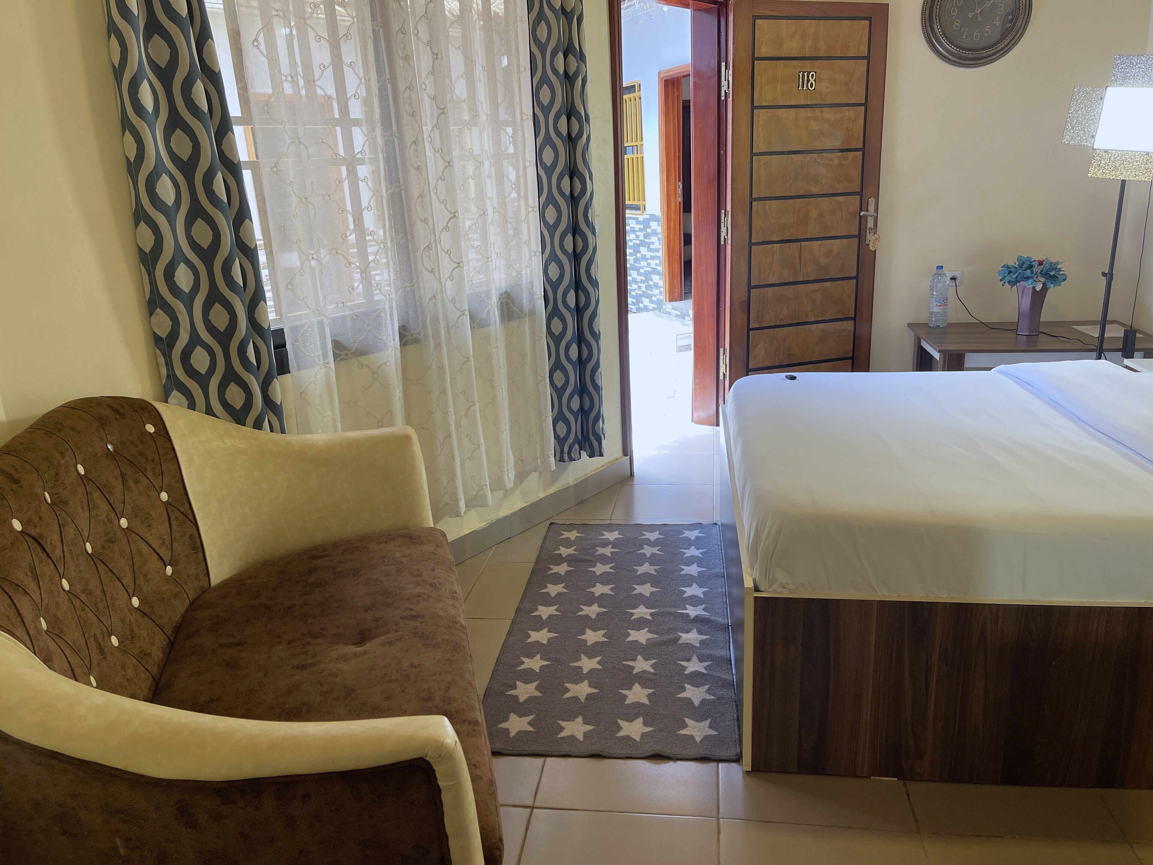 Une chambre à coucher comprenant un lit, une chaise, une armoire en bois et une porte donnant sur l’extérieur.