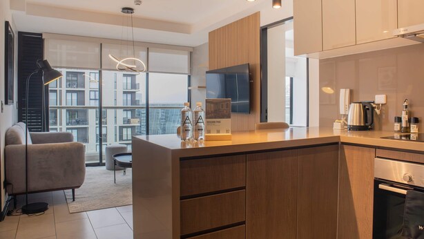 A modern kitchen with wooden cabinets, a built-in oven, and a large window overlooking a cityscape. - Incredible 2BR With Balcony in San Isidro (Lima)