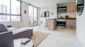 Een modern appartement met een zithoek, keuken en grote ramen met uitzicht over de stad.