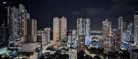 A nighttime cityscape with high-rise buildings, busy streets, and illuminated windows.