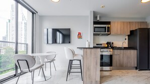 Een moderne keuken met een groot eiland, een flatscreen televisie en een zithoek met twee stoelen.