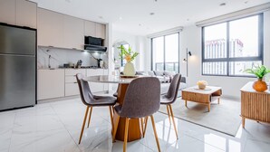 Cozinha moderna com área de refeições, janelas amplas e vista para edifícios.