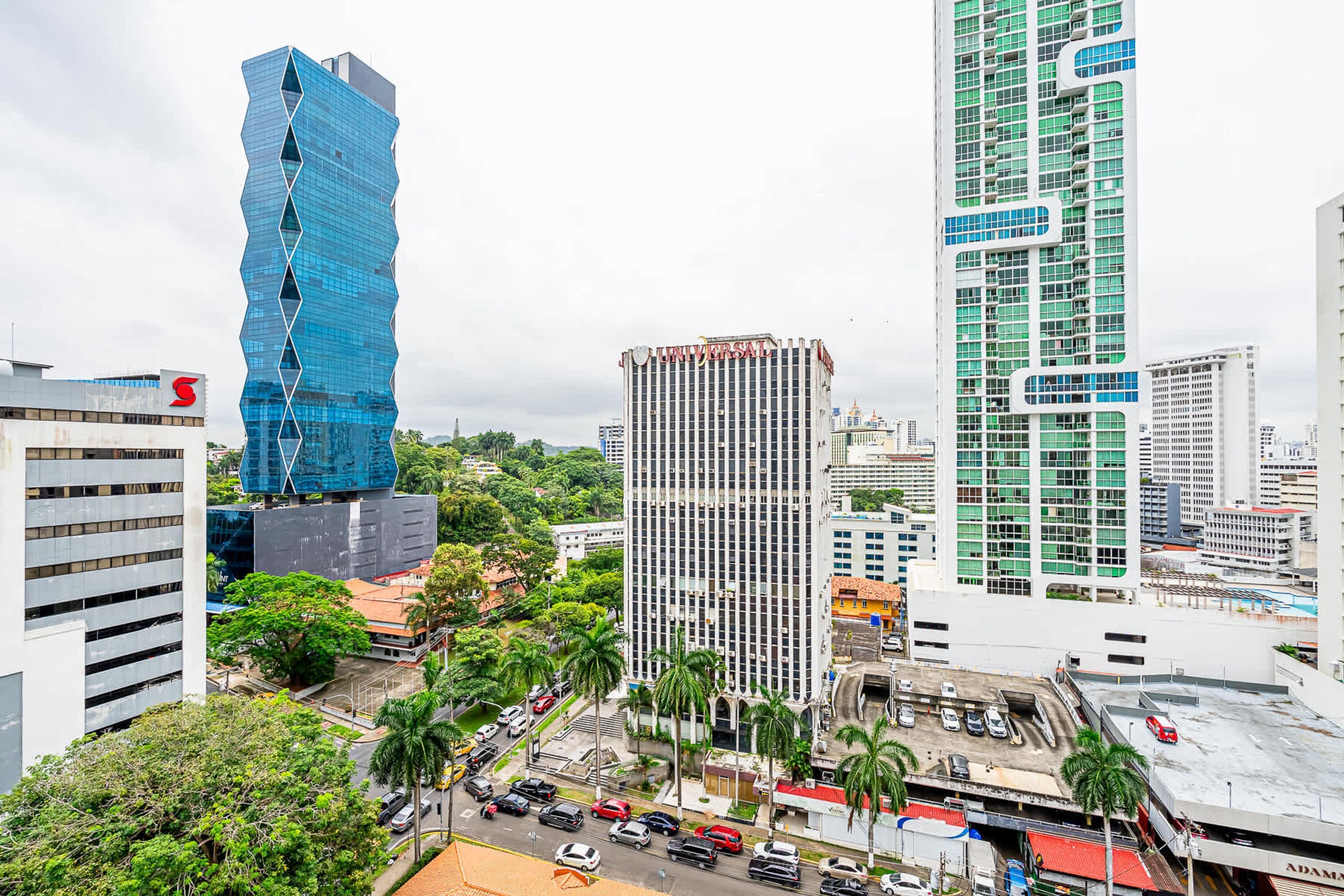 Un paisaje urbano con edificios altos y modernos, incluyendo un edificio de vidrio azul distintivo y un edificio blanco con el logotipo '5'.