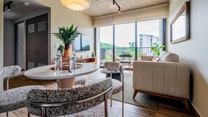 A modern living room with a round table, patterned chairs, a sofa, and a large window offering a view of buildings and greenery. - w Modern 2BR w Great Deco in Centriqo (Veracruz)