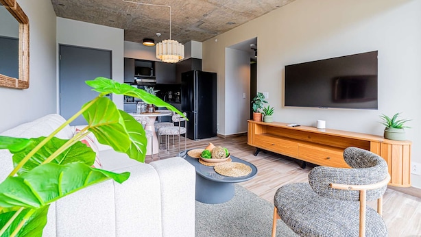 A modern living room with a large TV, a dining area, and a kitchen in the background. - w Modern 2BR w Great Deco in Centriqo (Veracruz)
