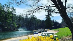 Un parc au bord du lac, équipé de tables de pique-nique, d’un bateau et d’une fontaine.