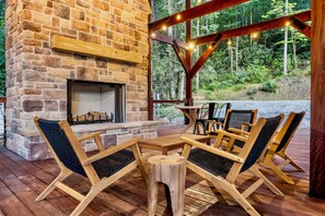 Una chimenea de piedra con una mesa y sillas en una zona de terraza de madera.