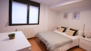 A bedroom with a bed, bedside tables, a radiator, a window, and a desk with a plant. - Your Central Base in Historic Tarazona (Tarazona)