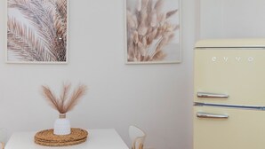 A dining area with a white table, a woven placemat, and a vase with pampas grass. There are two framed botanical prints on the wall and a vintage cream-colored refrigerator with the brand name 'evyo'. - Your Central Base in Historic Tarazona (Tarazona)
