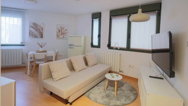 A modern living room with a sofa, a small round table, a TV, and a radiator. - Your Central Base in Historic Tarazona (Tarazona)