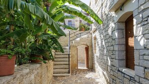 Un estrecho callejón empedrado de piedra con una puerta de madera y escalones que conducen a un edificio.