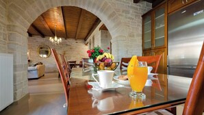 Un ambiente para desayuno con pared de piedra, techo de madera y una cocina moderna con refrigerador de acero inoxidable.