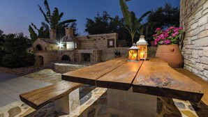 Un patio al aire libre con chimenea de piedra, una mesa de madera y un farol.