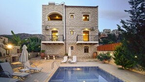Un edificio de piedra de dos pisos con piscina, asientos al aire libre y vistas del paisaje circundante.