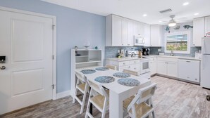 A modern kitchen with white cabinets, a dining table with chairs, and a built-in oven. - Seashells #45-Sanibel Condo with Gulf Access! (Sanibel)