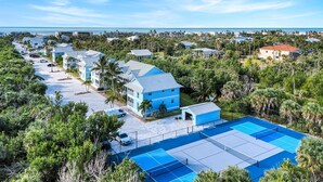 A residential area with multiple houses, a tennis court, and a view of the ocean. - Seashells #45-Sanibel Condo with Gulf Access! (Sanibel)