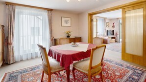 Un comedor con una mesa redonda, sillas, una araña y vista a otra habitación.