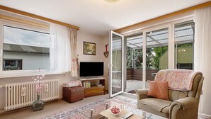 Una sala de estar con sofá, televisor y una mesa de vidrio.